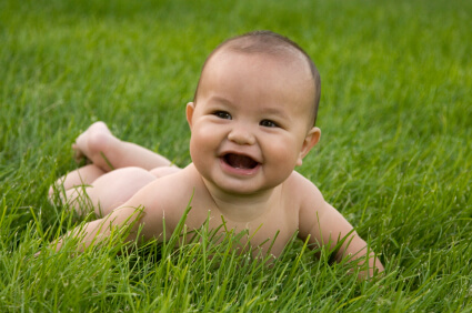一个微笑的婴儿躺在绿色的草地上。